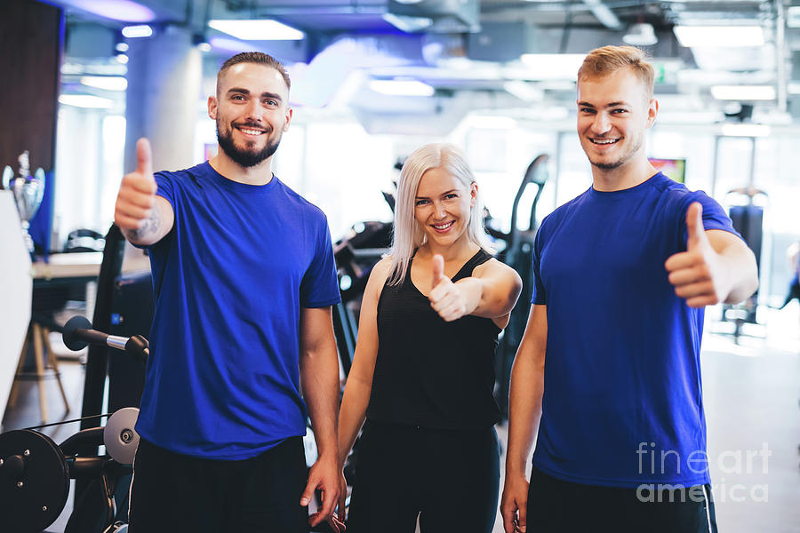 Three happy people at the gym showing thumbs up. Photograph by Michal Bednarek