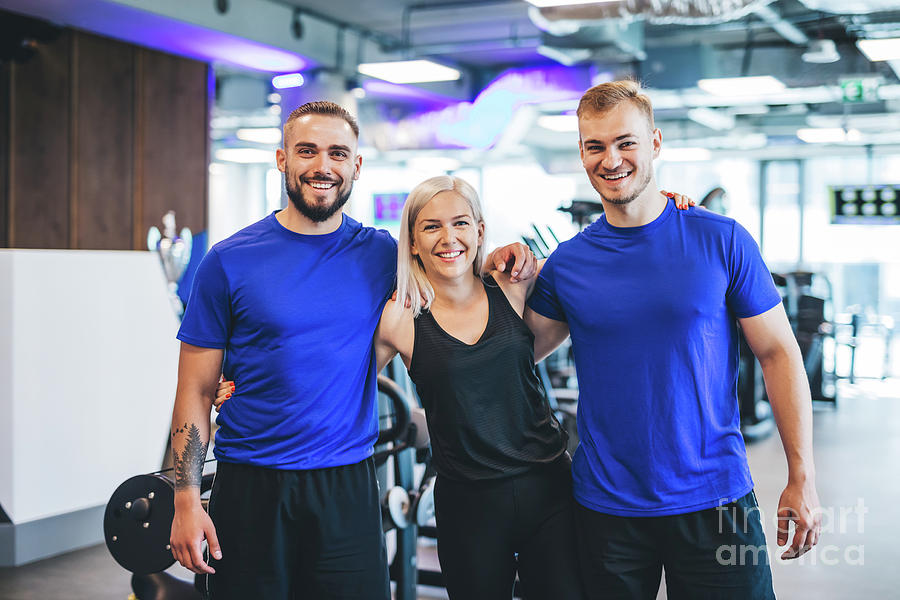 Three happy young people standing at the gym. Photograph by Michal Bednarek