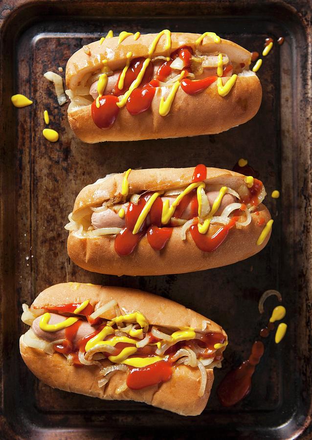 Three Hot Dogs In Buns With Ketchup, Mustard And Onions On A Vintage Baking Tray Photograph by Stacy Grant