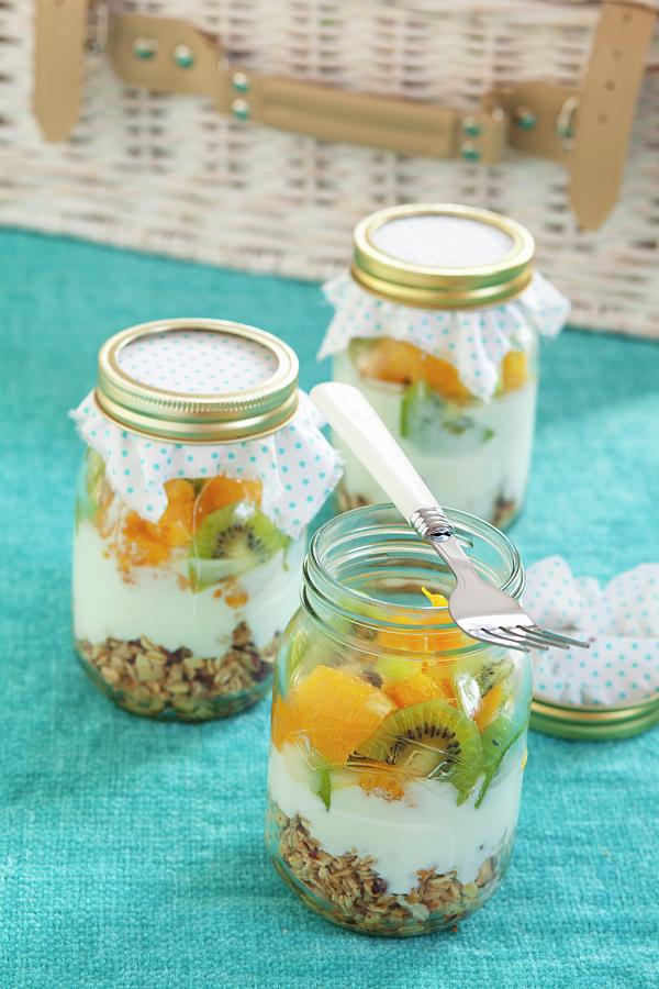 Three Jars Containing Ingredients For Muesli: Rolled Oats, Yoghurt, Kiwi And Orange Photograph by Studio Lipov