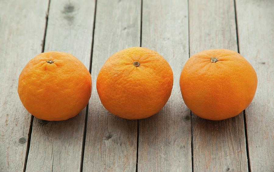 Three Mandarins On A Wooden Surface Photograph by William Boch