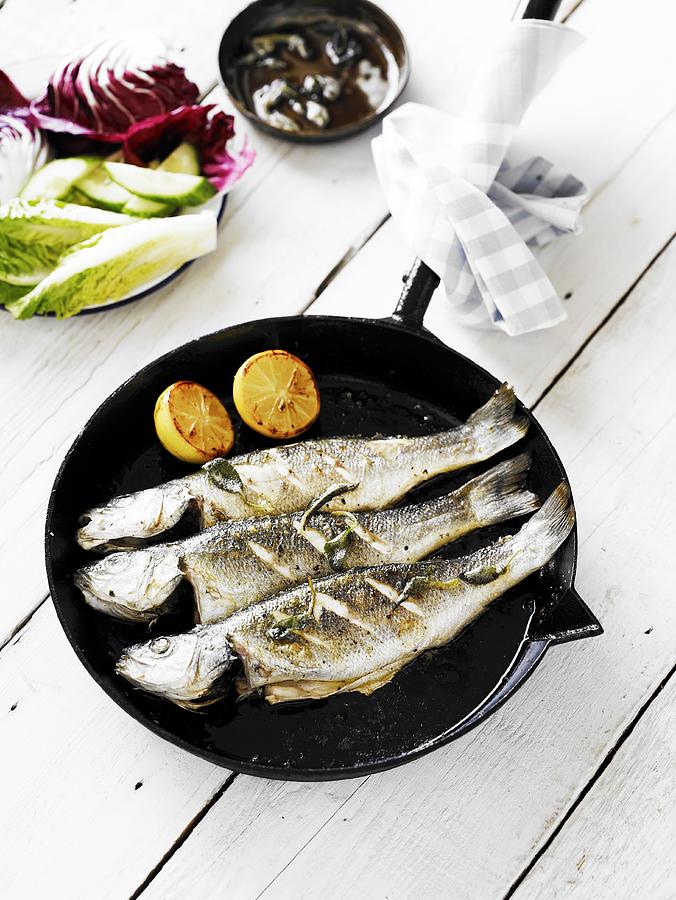 Fish Photograph - Three Panfried Whole Bass, Served In A Cast-iron Pan by Will Shaddock Photography