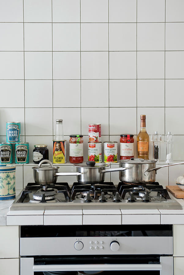 Three Pans On Gas Hob And Canned Groceries In White-tiled Kitchen Photograph by Magdalena Bjrnsdotter