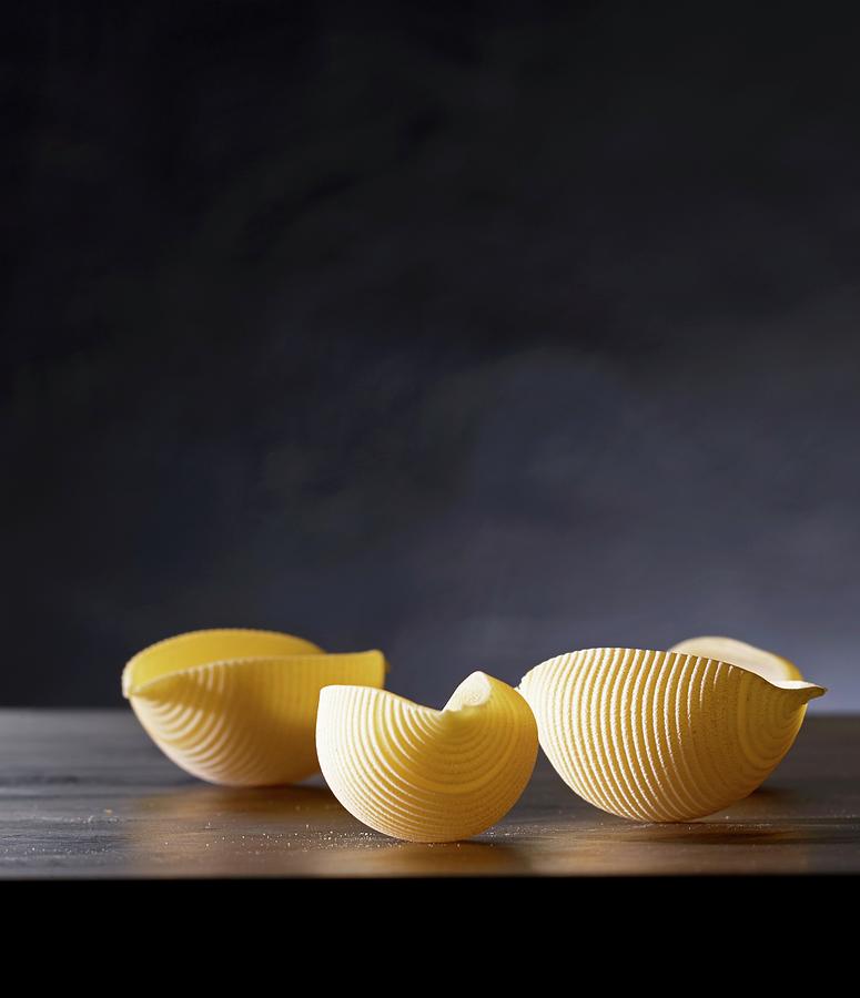 Three Pieces Of Uncooked Conchiglie Pasta With A Dark Background Photograph by Ludger Rose