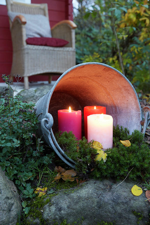 Three Pillar Candles In Zinc Bucket Lying On Side In Garden Photograph by Greenhaus Press