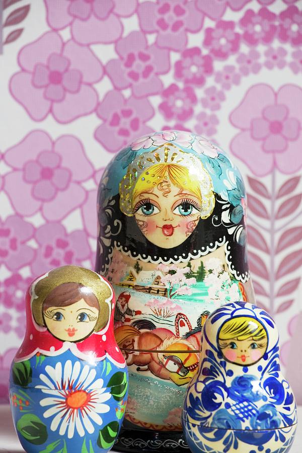 Three Russian Dolls In Front Of Pink Floral Wallpaper Photograph by Guy Obijn