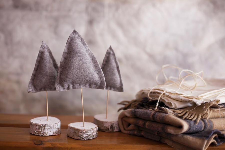 Three Small Felt Christmas Trees Next To Folded Woollen Blankets Photograph by Alicja Koll