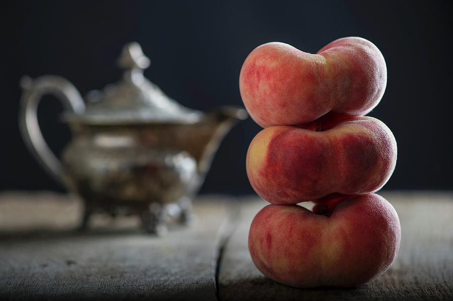 Three Stacked Vineyard Peaches In Front Of A Teapot Photograph by Nitin Kapoor