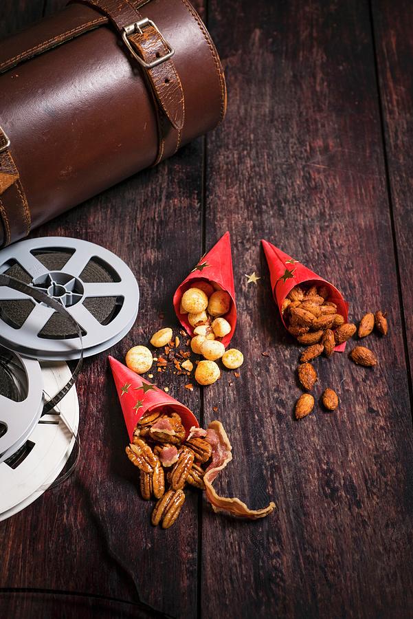 Three Types Of Nuts In Paper Bags Next To Film-themed Decorations Photograph by Great Stock!