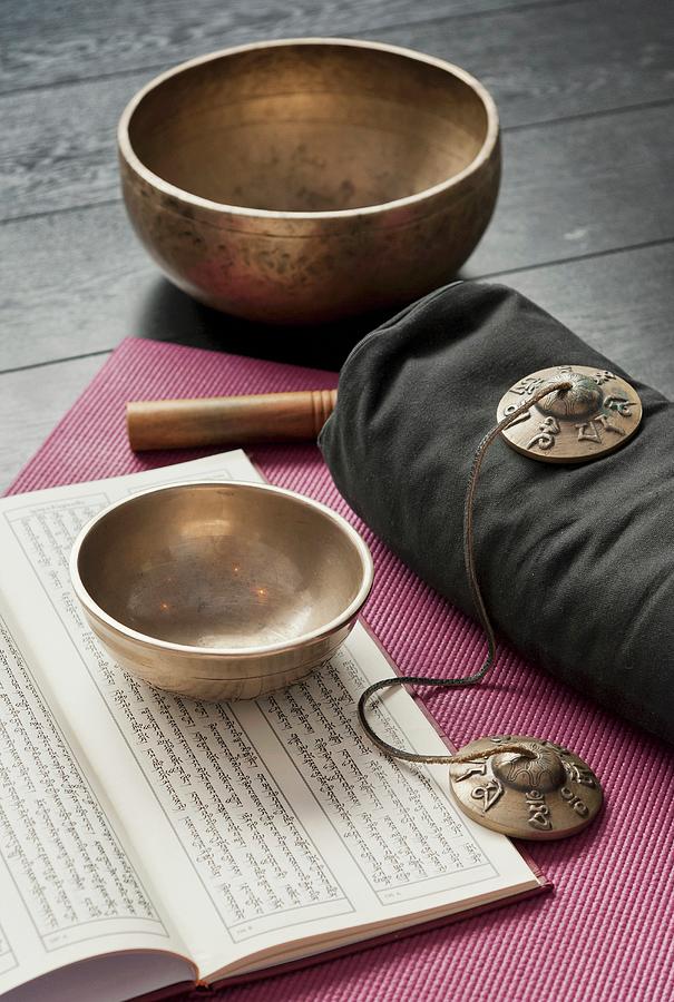 Tibetan Bowls, Cymbals And An Open Book In Sanskrit On A Pink Yoga Mat Photograph by Anthony Lanneretonne
