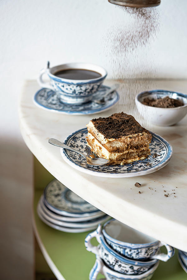 Tiramisu Slice On A Blue Plate On Marble With Coffee And Chocolate Powder Falling Photograph by Giulia Verdinelli Photography