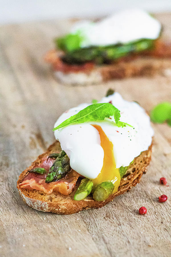 Toasts With Green Asparagus Bacon And Poached Egg With Pouring Yolk Photograph by Karolina Nicpon