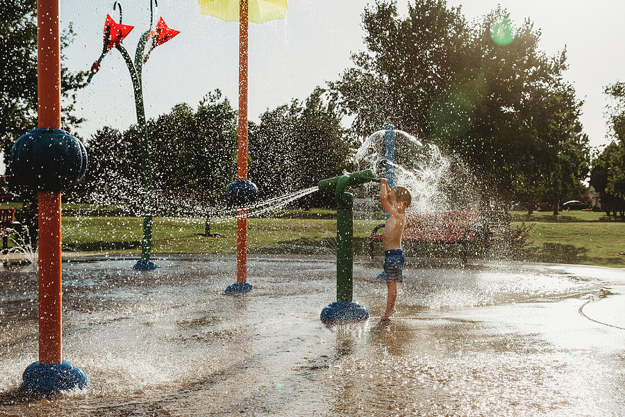 Sunset Photograph - Toddler Boy Playing With Water Toy At Splash Pad by Cavan Images
