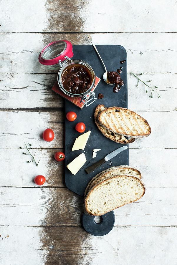 Tomato Chutney In A Jar And On A Spoon With Slices Of Bread And Cheese Photograph by Magdalena Hendey
