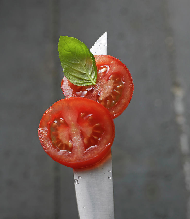 Tomato Slices With A Basil Leaf On A Knife Tip With Water Droplets Photograph by Ludger Rose