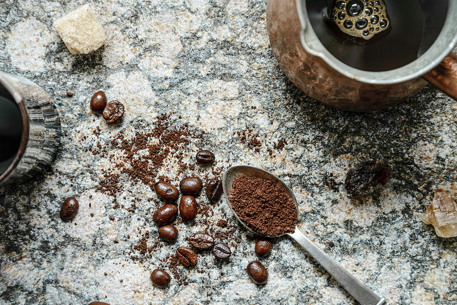 Top Down View Of Scattered Coffee Beans, Ground Coffee In A Spoon, Brewed Coffee In Jezva On A Granite Surface Photograph by Albina Bougartchev
