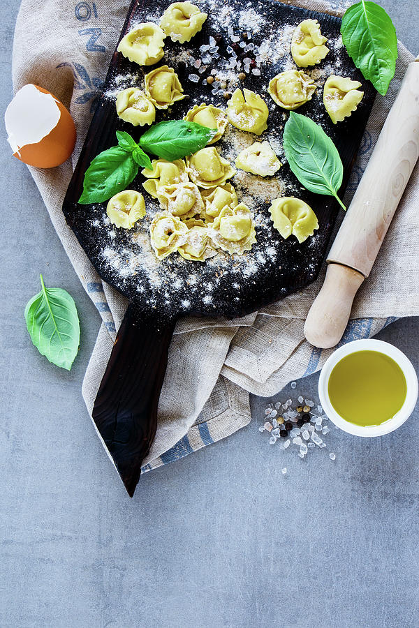 Top View Of Freshly Made Raw Italian Pasta Tortellini, Olive Oil, Flour And Basil Leaves On Light Grey Vintage Background Photograph by Yuliya Gontar