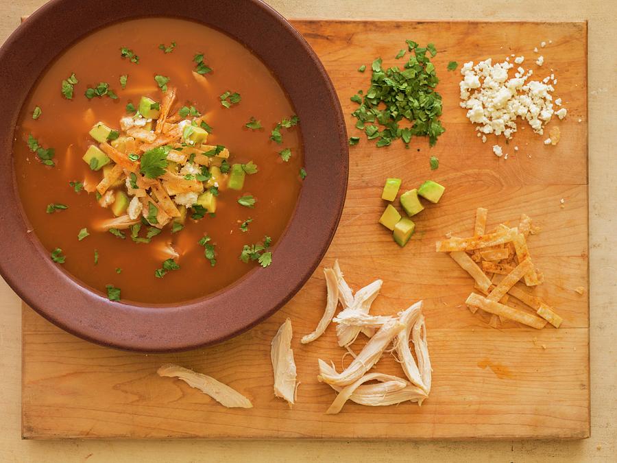 Tortilla Soup On A Chopping Board With Garnishes chicken, Tortilla Strips, Avocado, Coriander And Cheese Photograph by Don Crossland