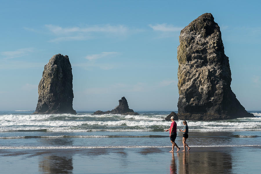 Tourists Pass By The Unique Rocks In The Water Of The Pacific Occannon Beach, Oregon, Usa - October Photograph