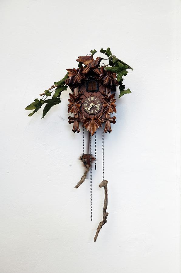 Traditional Black Forest Cuckoo Clock With Root Wood Pendulum Weights And Decorated With Ivy On White Wall Photograph by Lioba Schneider Fotodesign