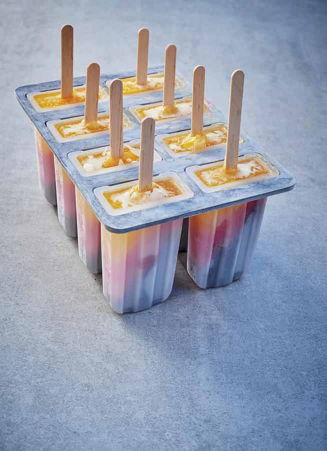 Tri-coloured Ice Cream Sticks In Lolly Moulds On A Grey Surface Photograph by Stefan Schulte-ladbeck