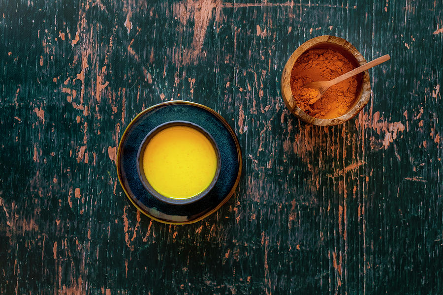 Turmeric Golden Milk On Saucer And Distressed Green Wooden Surface Photograph by Hein Van Tonder