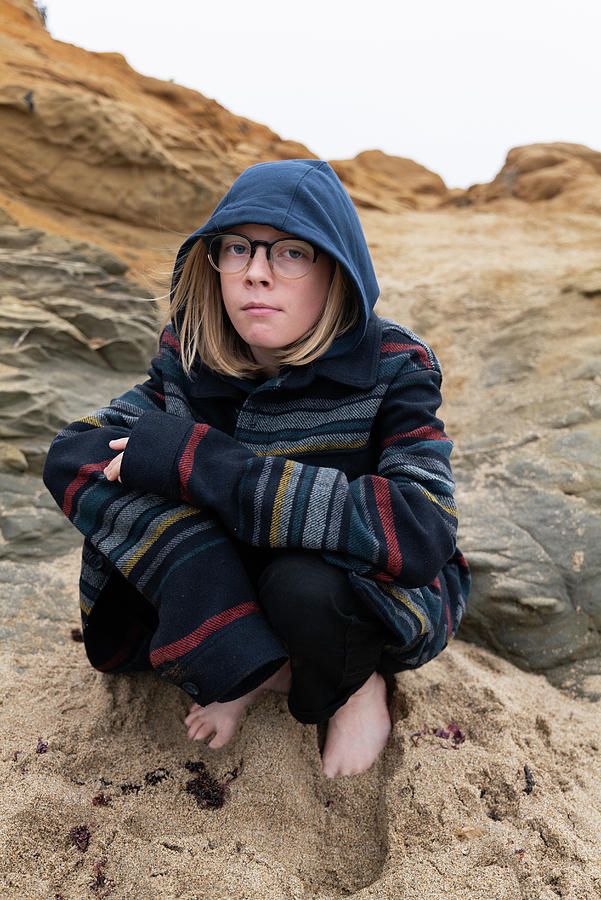 Tween Crouching In Sand On Beach Looking At Camera Wearing Glasses