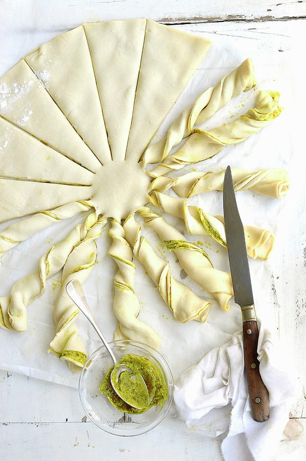 Twisting Slices Of The Filo Pastry With The Pesto To Shape The Sun Beams Photograph by Keroudan