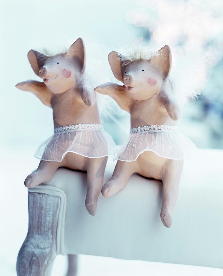 Two Angel-pig Ornaments Arranged On White Upholstered Chair Photograph by Matteo Manduzio