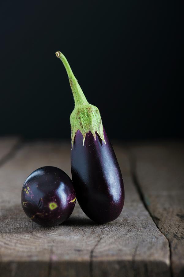 Two Baby Aubergines On A Wooden Tabletop Photograph by Nitin Kapoor