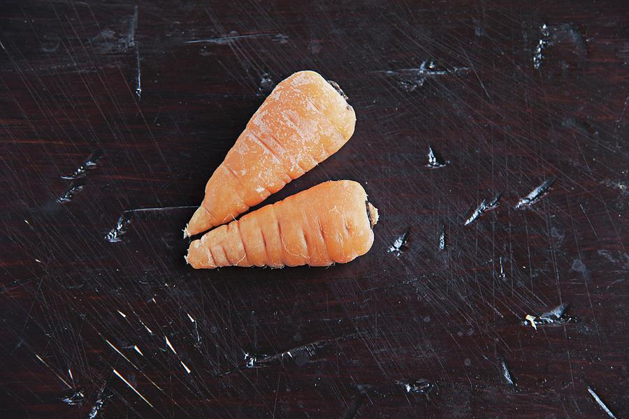 Two Baby Carrots On A Wooden Surface Photograph by Richard Church