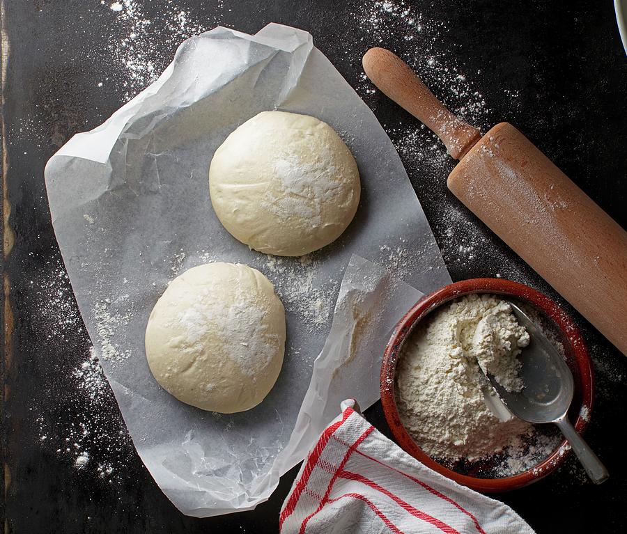 Two Balls Of Pizza Dough On A Piece Of Paper With Flour And A Rolling Pin Photograph by Ludger Rose