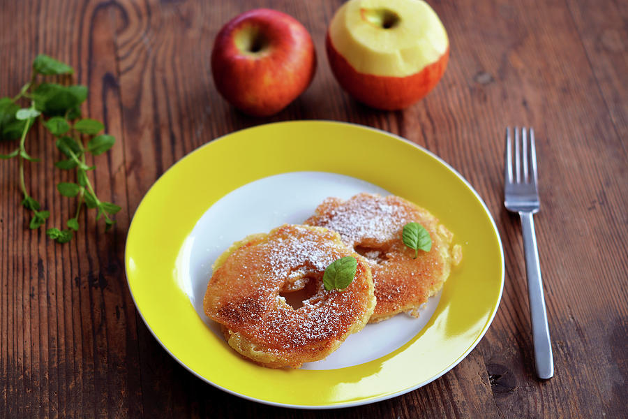 Two Battered Apple Rings With Sugar, Cinnamon And Mint On A Yellow Plate Photograph by Mariola Streim