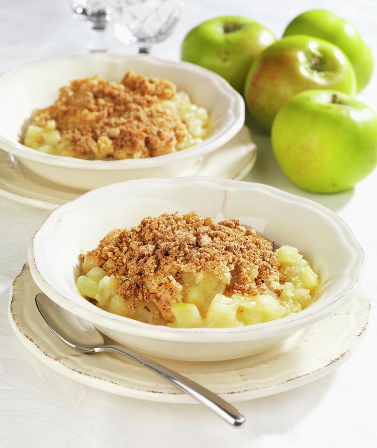 Two Bowls Of Apple Crumble With Fresh Apples Next To Them Photograph by Robert Morris