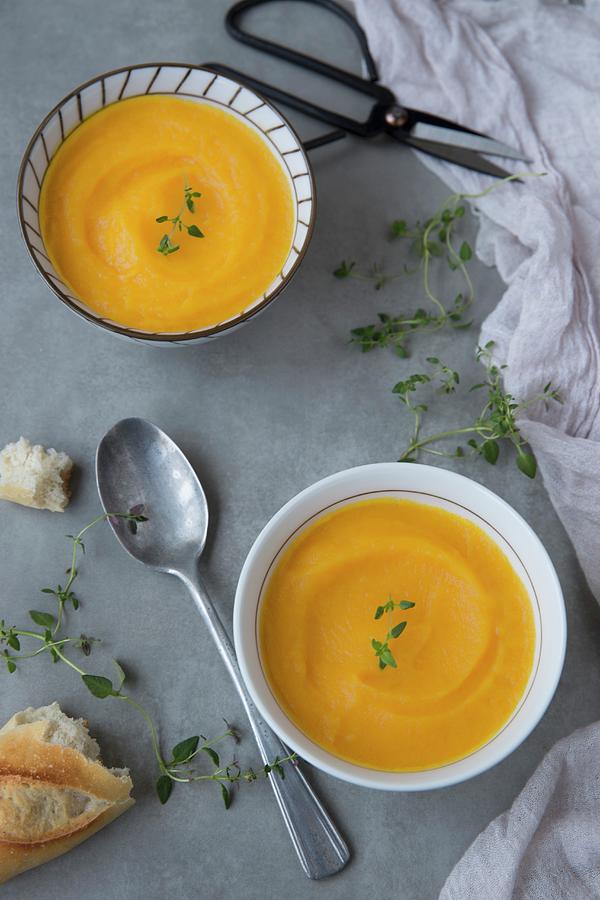 Two Bowls Of Cream Of Pumpkin Soup With Thyme And Baguette Photograph by Joana Leito