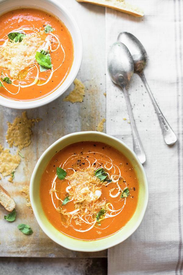 Two Bowls Of Tomato Soup Garnished With Parmesan Crisps, Sour Cream And Fresh Basil Photograph by Magdalena Hendey