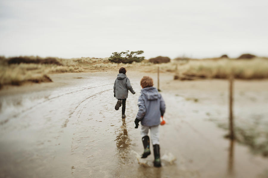 Two Boys In Winter Running Through Puddles On Sand Dune Saltmarsh ...