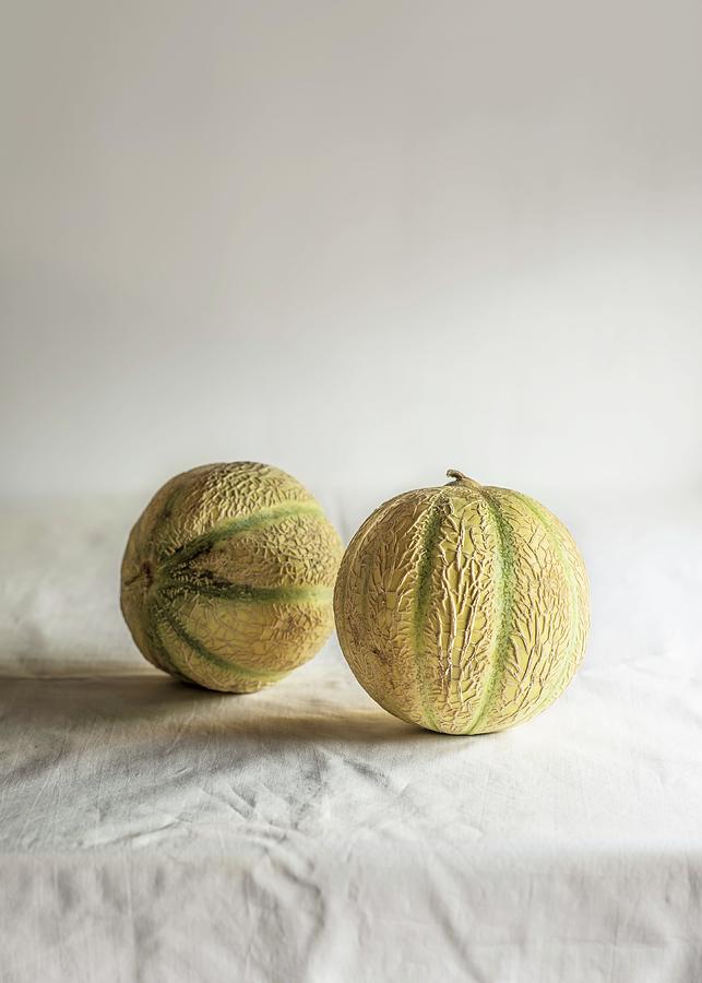 Two Cantaloupe Melons On A Tablecloth Photograph by Miriam Garcia