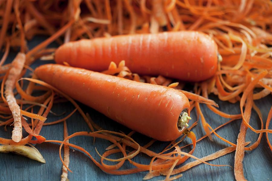 Two Carrots Next To A Mound Of Carrot Peelings Photograph by Martina Schindler