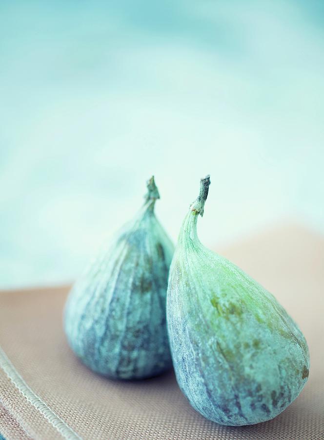 Two Figs On A Brown Tea Towel Against A Light Blue Background Photograph by Julian Winkhaus