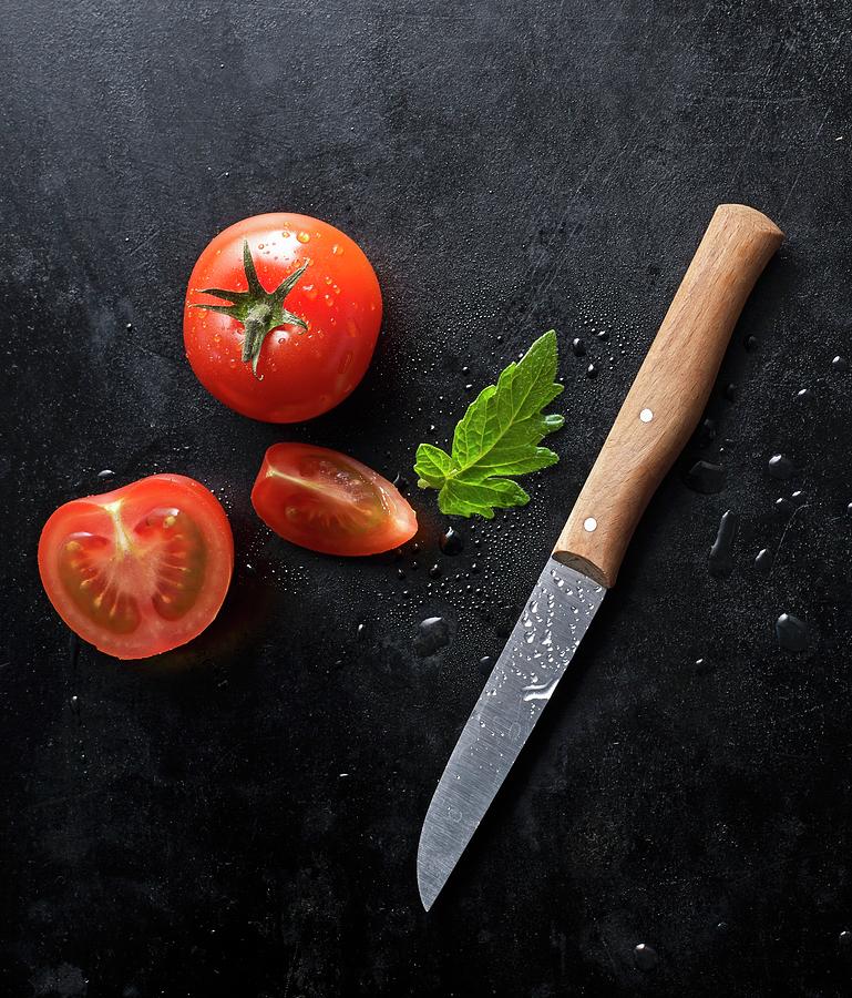 Two Fresh Tomatoes And A Knife On A Black Baking Tray Photograph by Ludger Rose