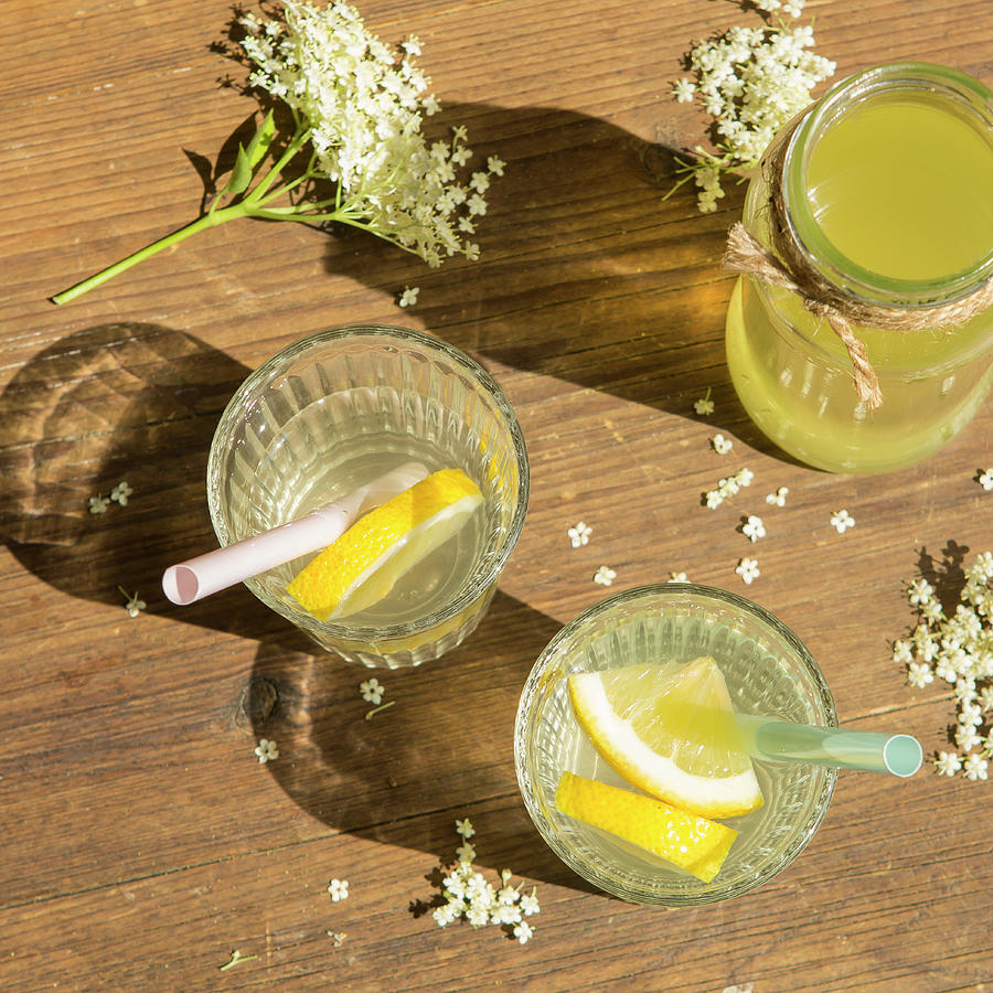 Two Glasses Od Mixed Elderflower Cordial And A Jar Of Fresh Cordial On A Wooden Table With Freshly Picked Elderflowers Photograph by Stacy Grant