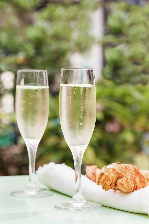 Two Glasses Of Prosecco On A Table Outside With Large Cheese Straws Photograph by Cath Lowe
