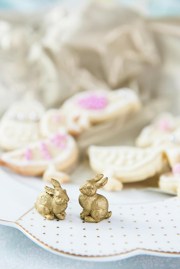 Two Golden Bunnies On Plate In Front Of Easter Biscuits Photograph by Ruud Pos