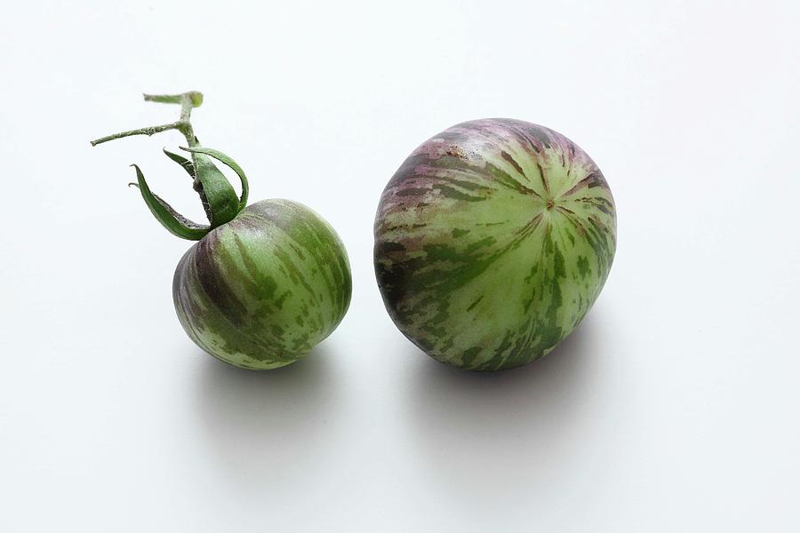 Two Green Striped Tomatoes On A White Surface Photograph by Jalag / Mathias Neubauer