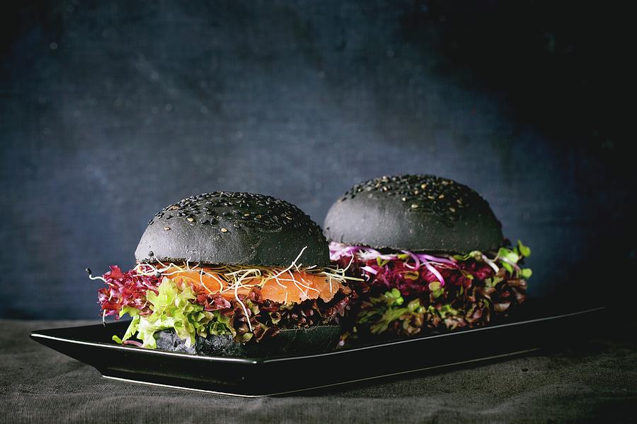 Two Homemade Black Burgers With Salmon, Beetroot, Sprouts And Lettuce Photograph by Natasha Breen
