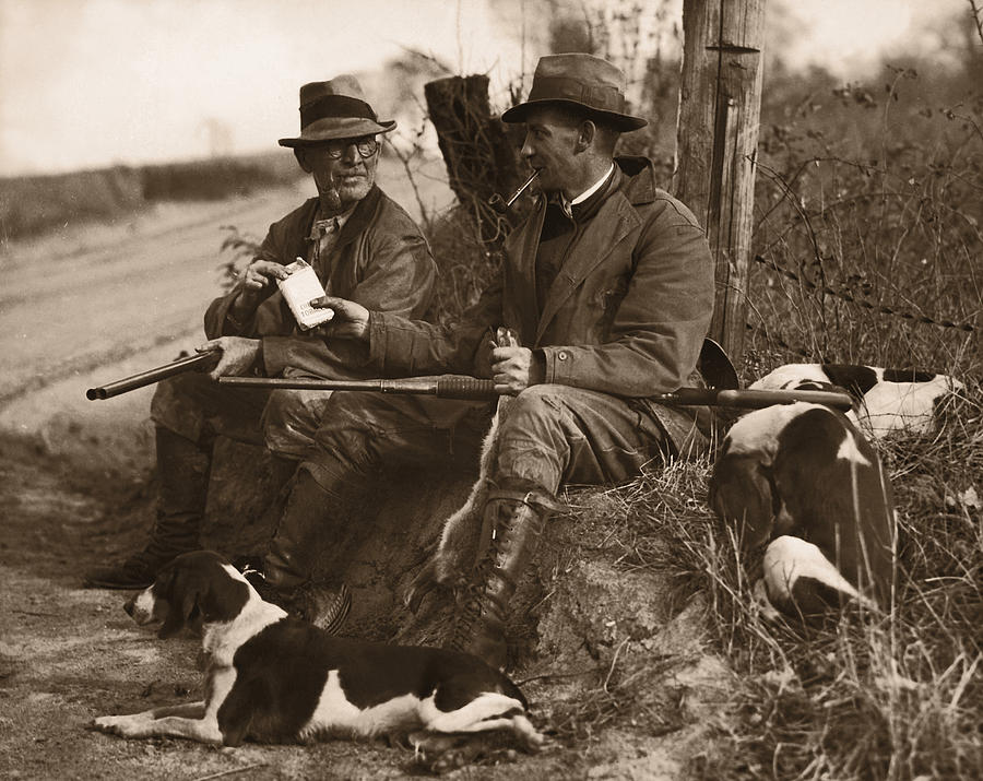 Black And White Photograph - Two Hunters With Dogs Sharing Cigars by Fpg
