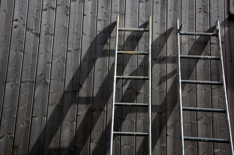 Two ladders are leaning against a wall in such a way that they