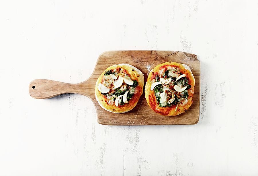 Two Mini Pizzas With Spinach And Garlic On A Kitchen Board Photograph by B.&.e.dudzinski