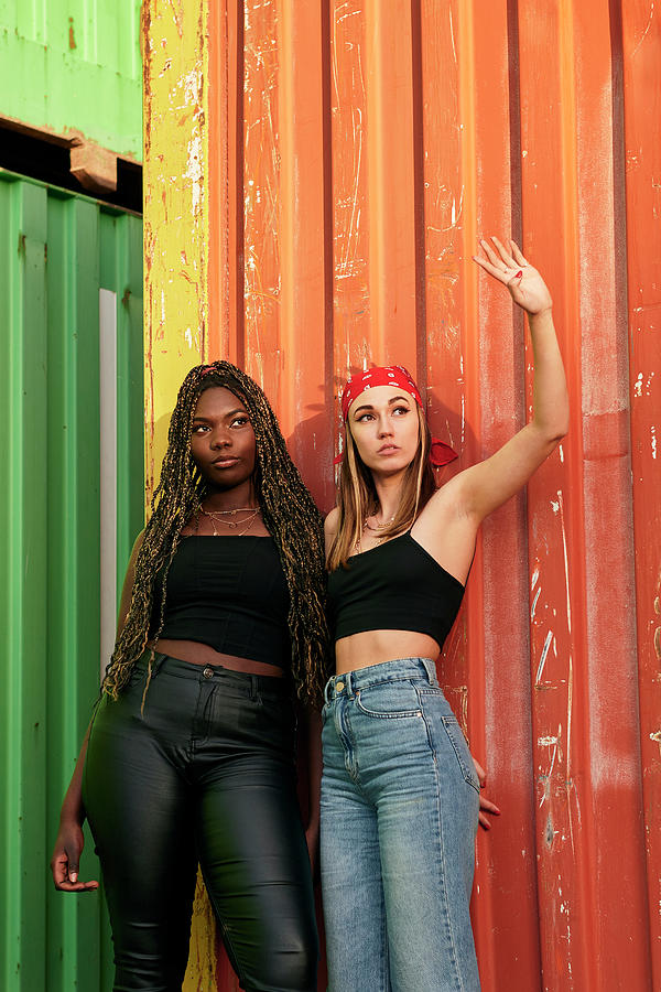 Sunset Photograph - Two Multi-ethnic Young Women In Urban Clothing Pose At Sunset by Cavan Images